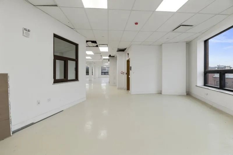 Empty white office corridor with large windows and overhead fluorescent lights