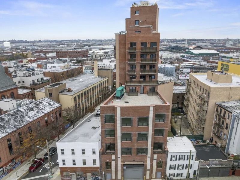 Aerial view of a snowy urban block with tall brick and beige apartment buildings.