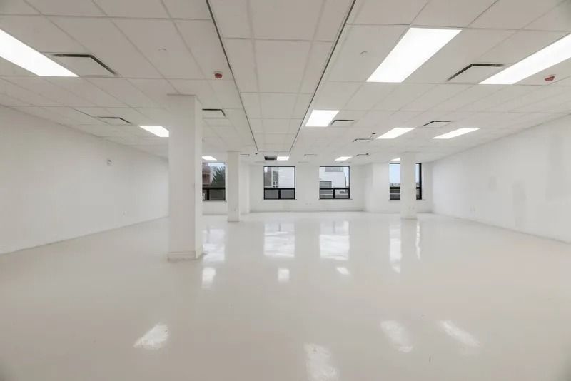 Empty bright office space with white walls, glossy floors, and large windows