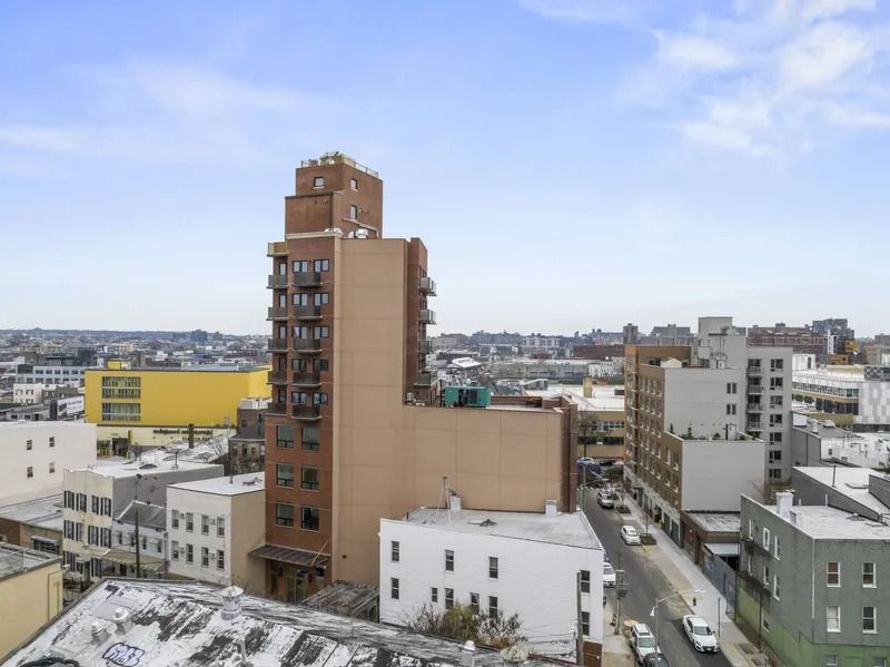 Snowy cityscape with a tall brown apartment building under a clear blue sky.