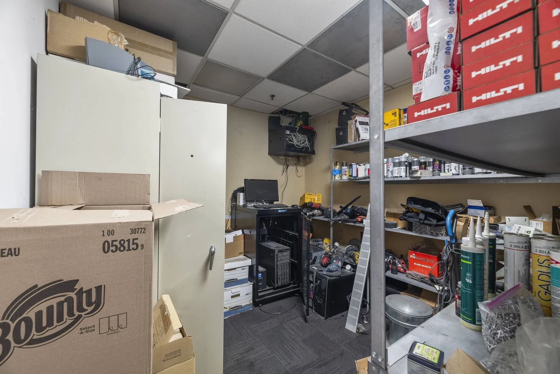 Storage room with shelves, boxes, and supplies, including paper towels and drink cases