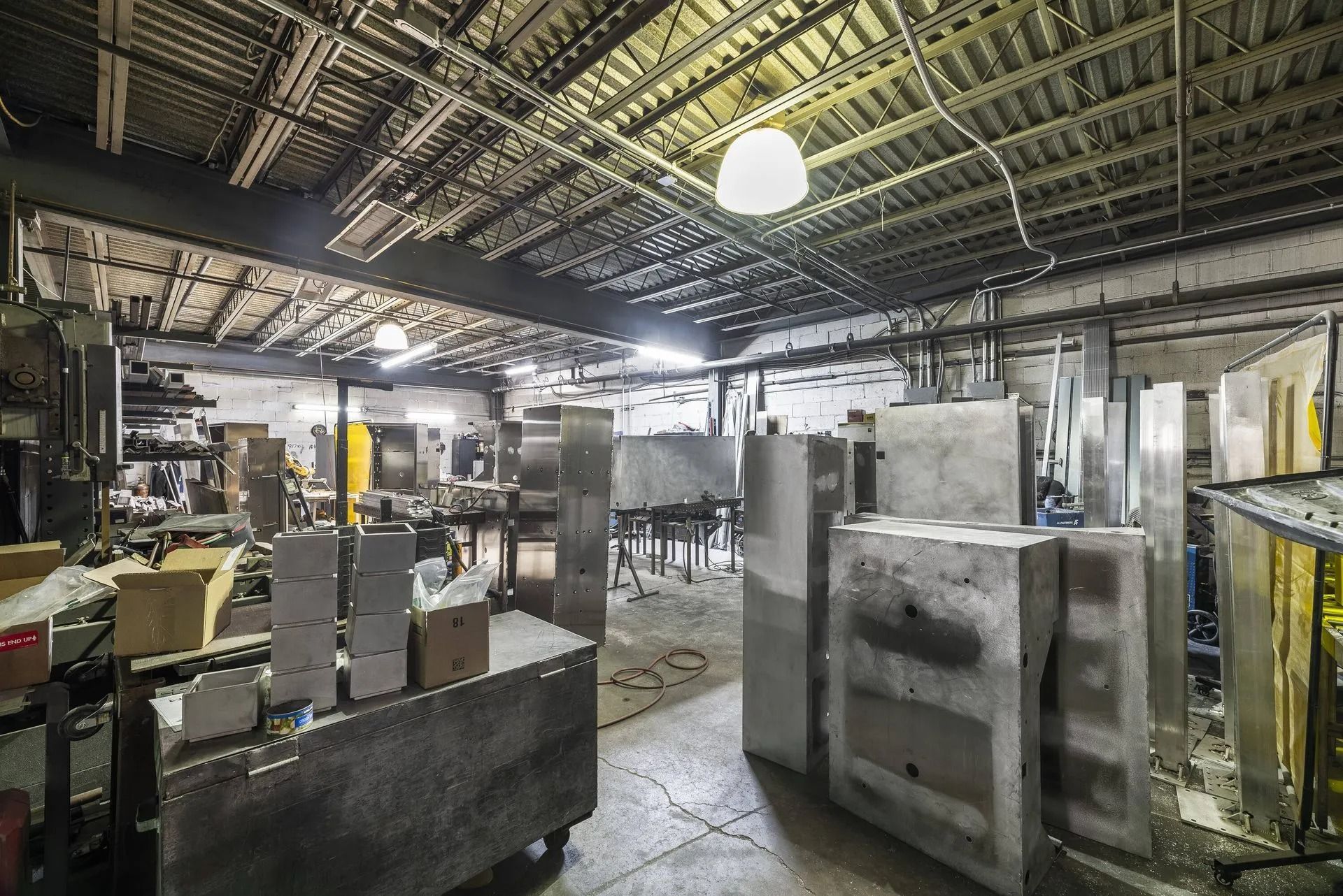 Industrial workshop interior with machinery, metal equipment, and fluorescent lighting
