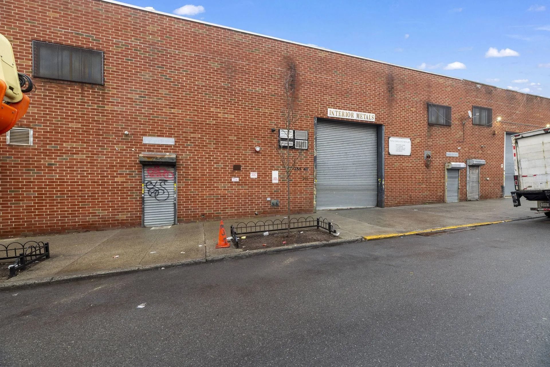 Brick warehouse exterior with a loading dock, roll-up door, and parked truck on wet pavement