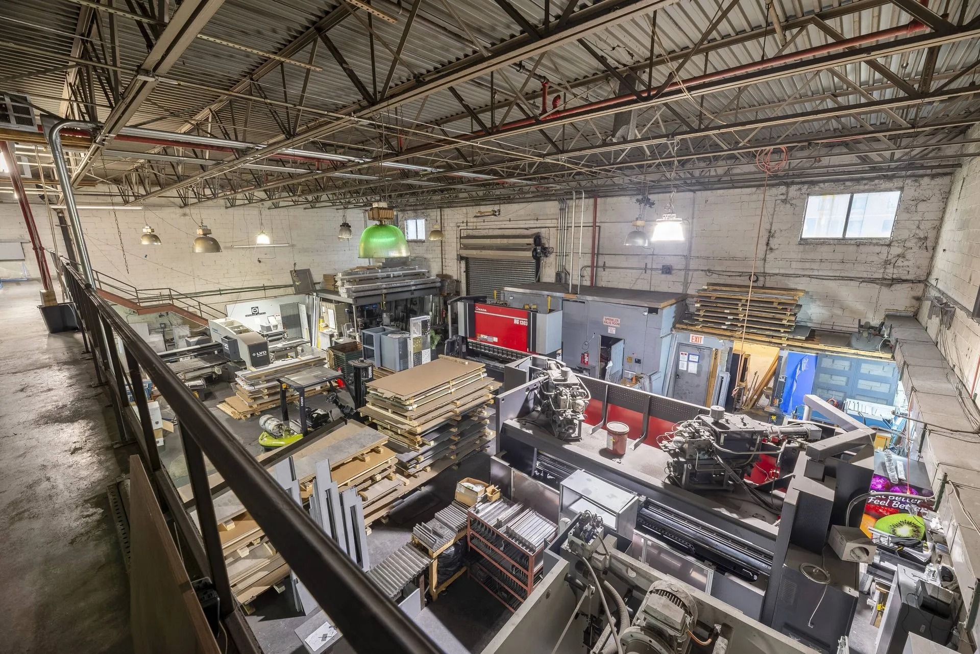 Large industrial workshop with machinery, workbenches, and metal equipment under a high ceiling