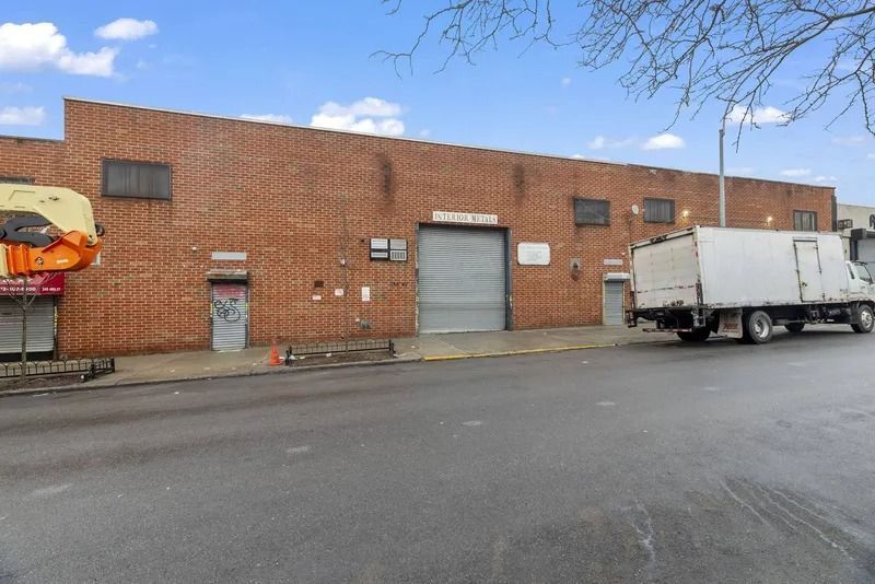 Brick warehouse loading dock with a white box truck parked beside a large roll-up door