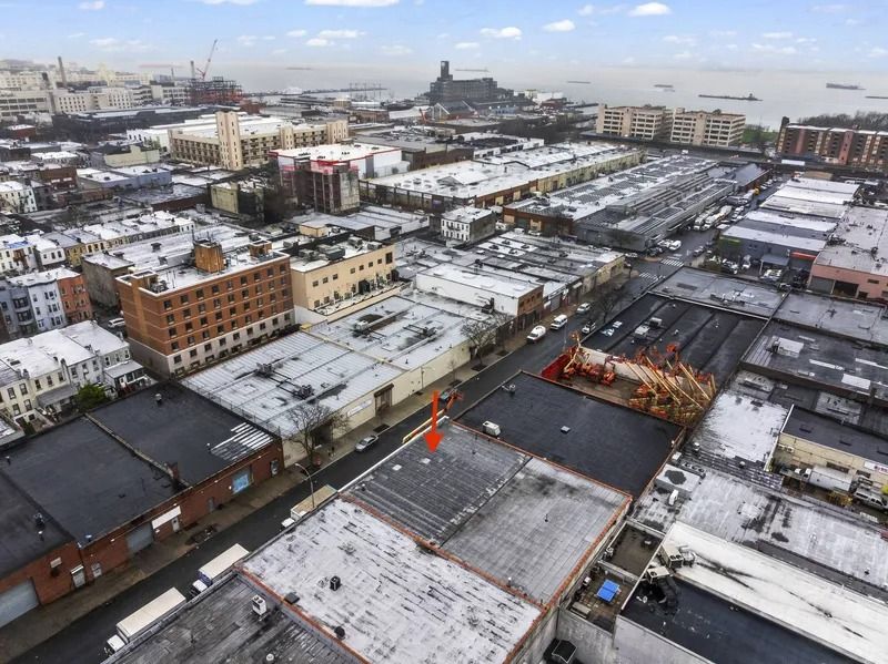 Snow-covered city rooftops and streets under a cloudy sky, viewed from above.