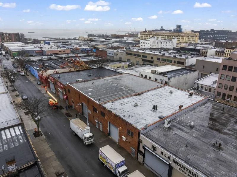 Panoramic view of an industrial area with warehouses, trucks, and roads under a cloudy sky.