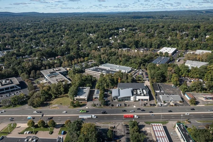 Aerial view of a suburban area with buildings, trees, and a highway with traffic.