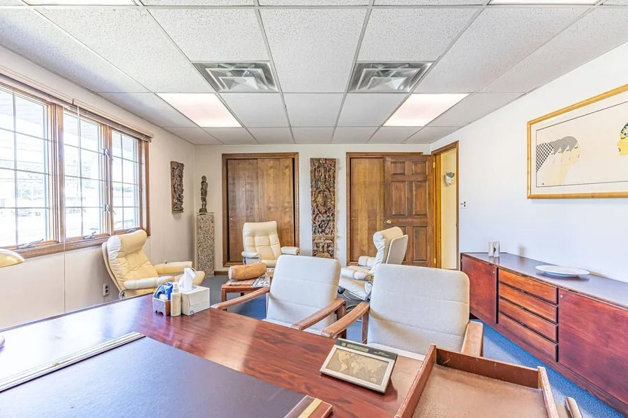Bright medical waiting room with chairs, desks, wooden doors, and large windows