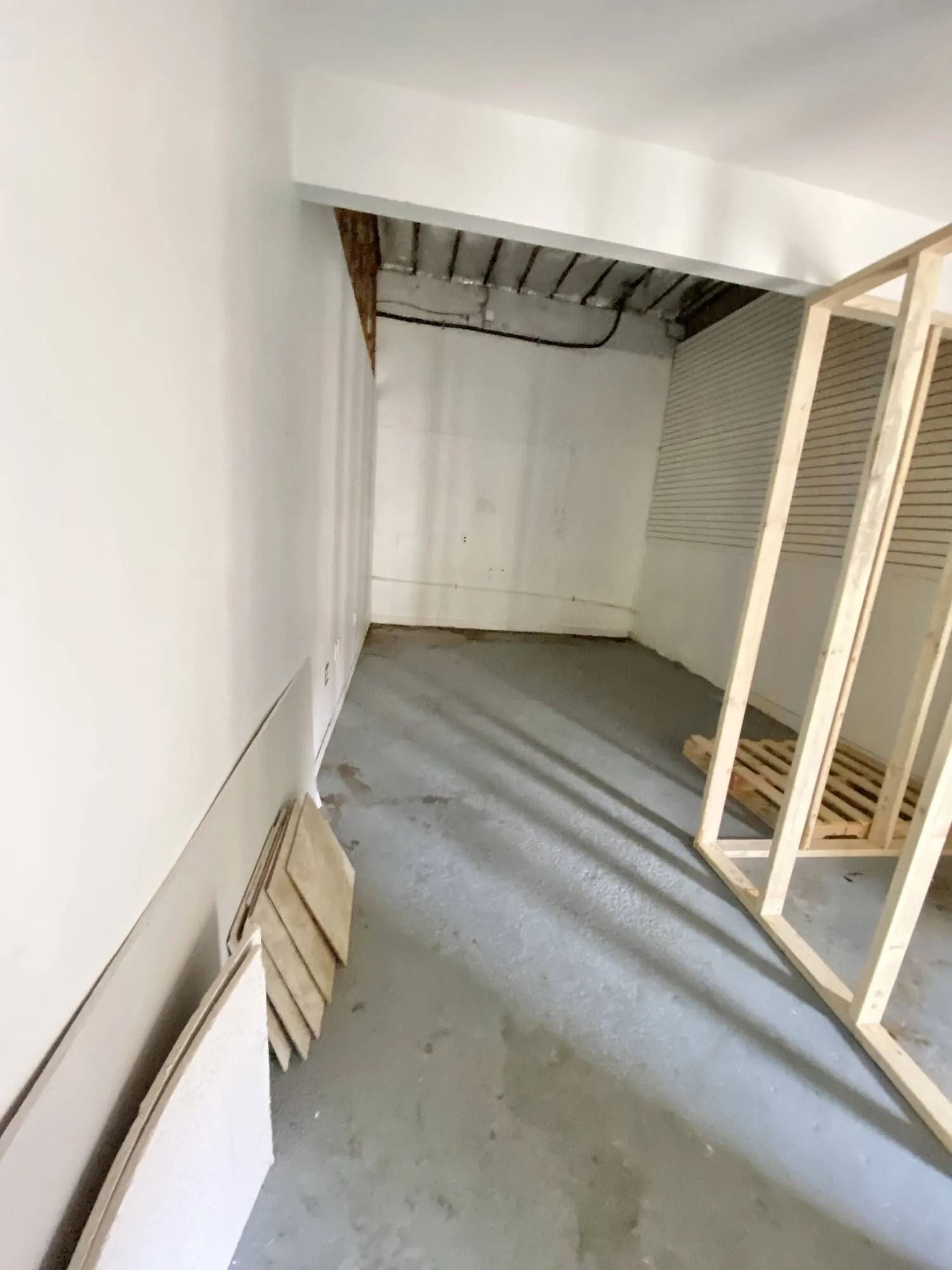 Empty white closet with gray floor and wooden shelving on the right