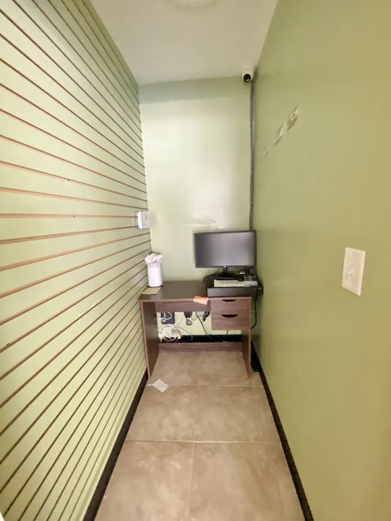 Narrow hallway with striped wall, small desk, computer monitor, and light green walls.
