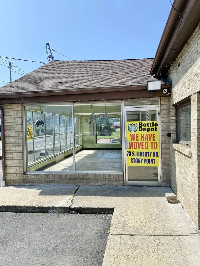 Closed storefront with a yellow “We have moved” sign beside a glass entrance.