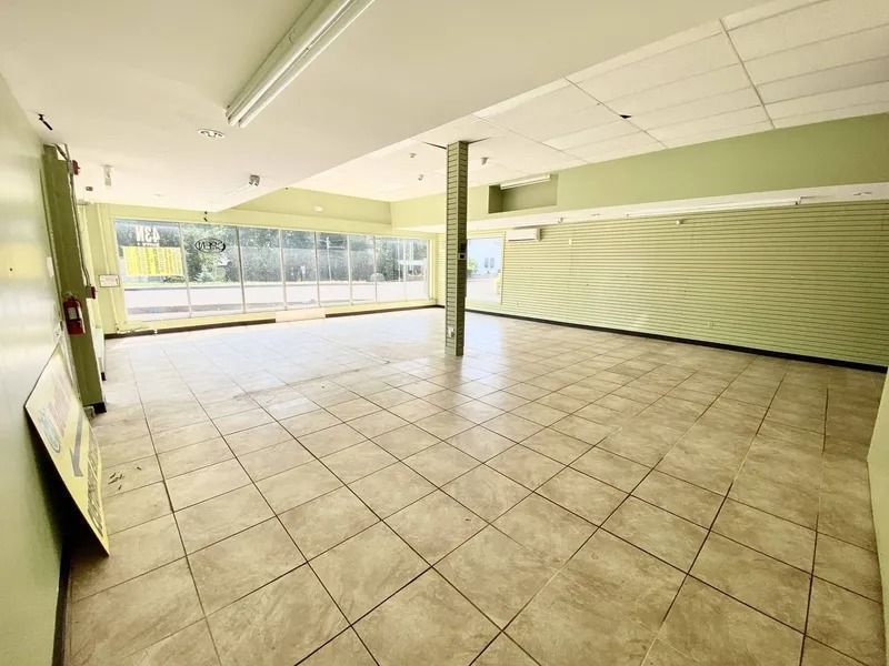 Empty tiled storefront interior with large front windows and green walls