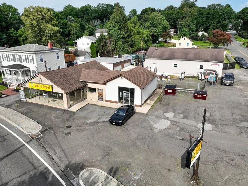 Aerial view of a small roadside business with parked cars and trees in the background.