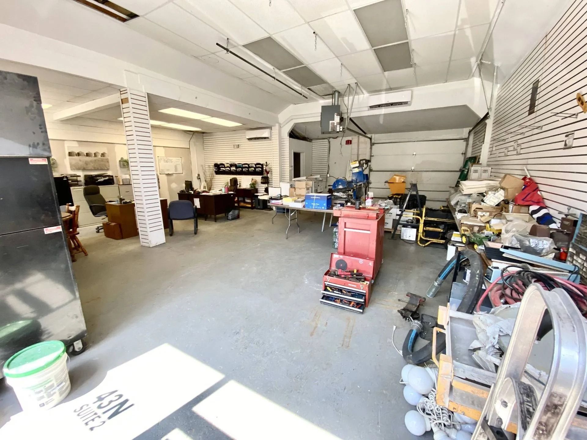 Wide garage workshop with tools, workbenches, shelves, and a red cart in the center