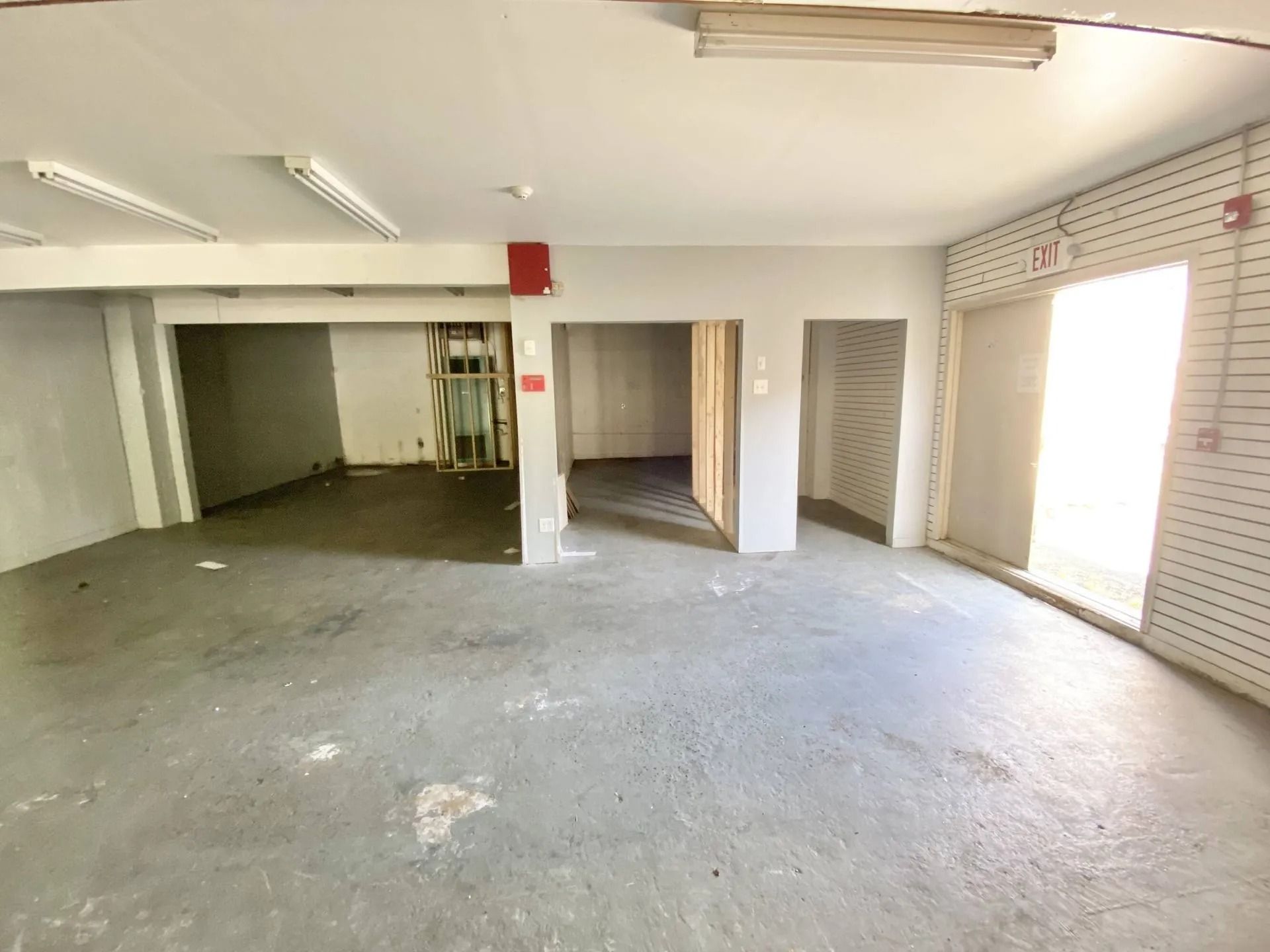 Empty warehouse room with concrete floor, white walls, and large open doorways