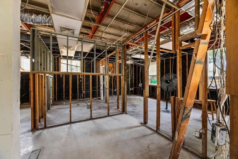 Interior of a building under construction with exposed framing, concrete floor, and unfinished ceiling.
