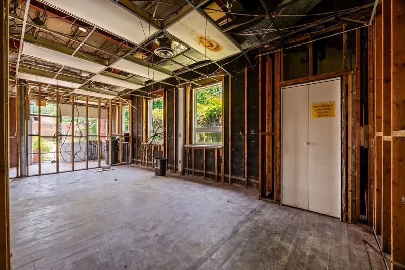 Unfinished room with exposed framing, concrete floor, and large windows overlooking a patio.