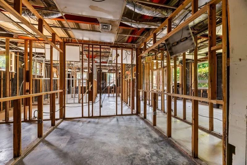 Exposed wooden framing inside a house under construction, with unfinished walls, ceiling, and concrete floor.