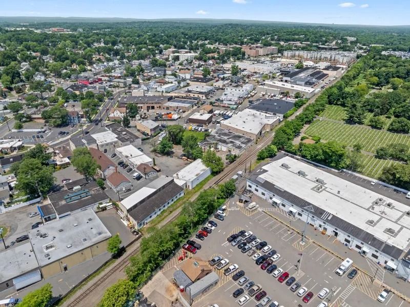 Aerial view of a small town with streets, buildings, parking lots, and green fields under a clear sky