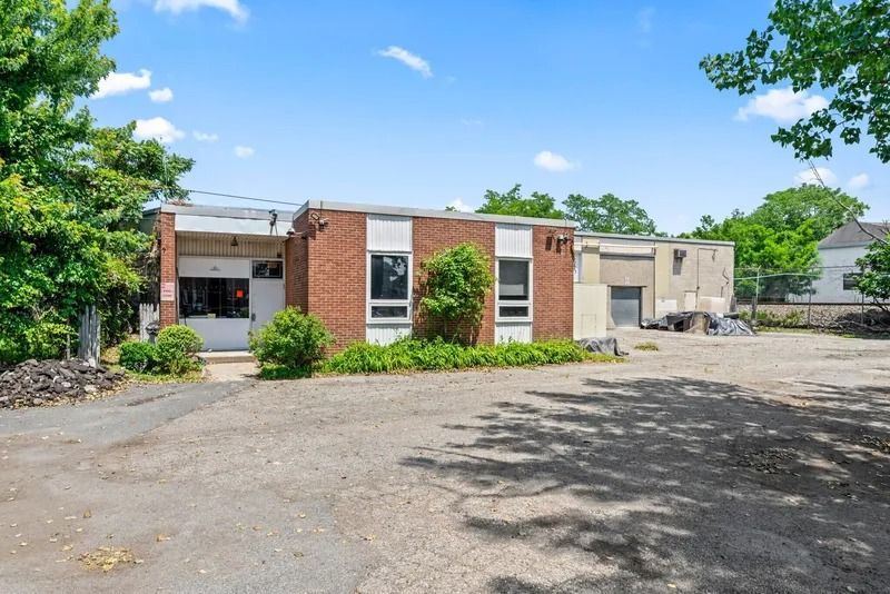 Single-story brick building with parking lot, trees, and blue sky