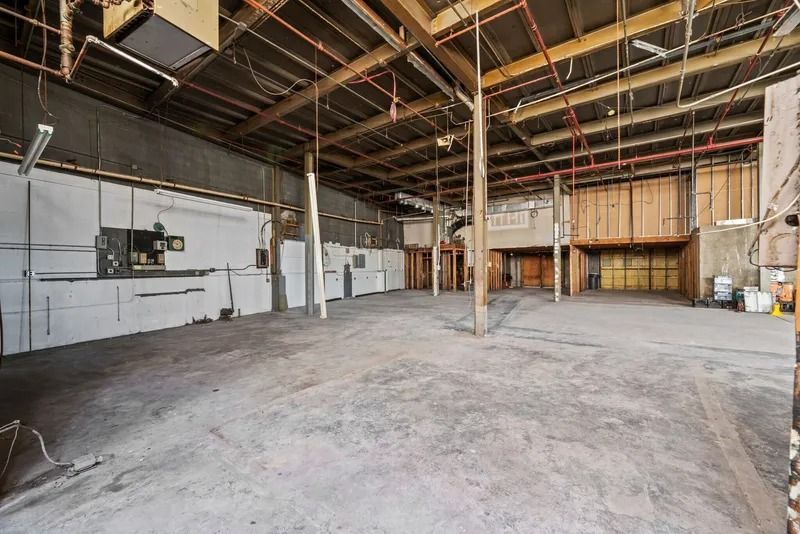 Empty industrial warehouse interior with concrete floor, exposed beams, and loading dock doors
