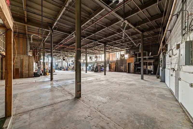 Empty industrial warehouse with concrete floor, exposed beams, and brick walls