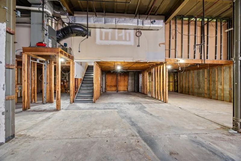 Interior of an unfinished building with exposed framing, stairs, and concrete floors
