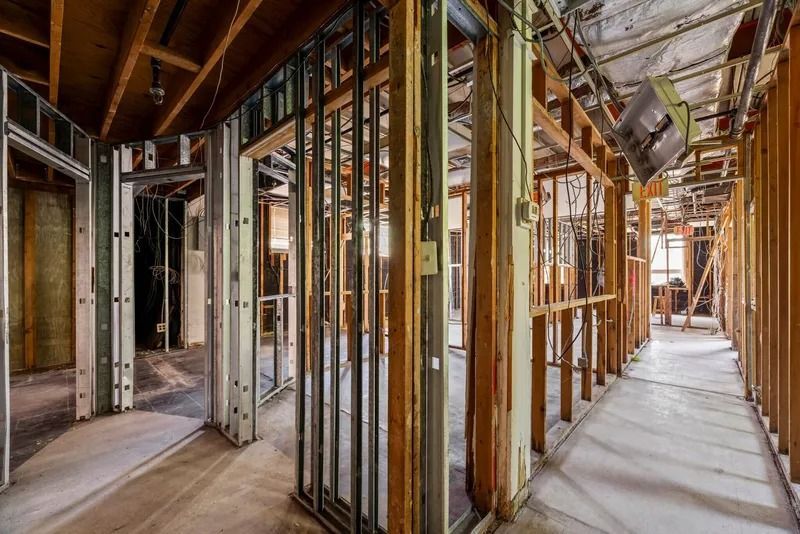 Interior of a house under construction, with exposed framing, wiring, and unfinished hallways