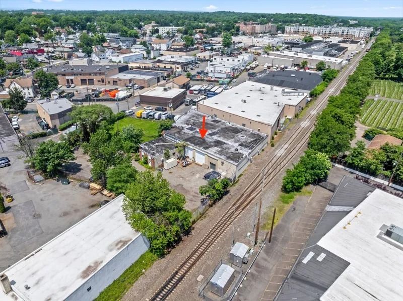 Aerial view of an urban neighborhood with buildings, trees, and train tracks running through the center.