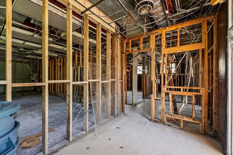 Interior of a building under construction with exposed wooden framing, wiring, and unfinished walls