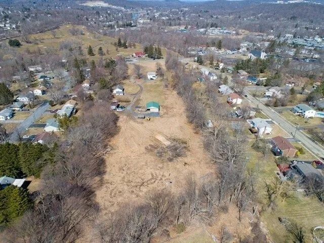 Aerial view of a suburban neighborhood with a large grassy open lot in the center and houses on both sides