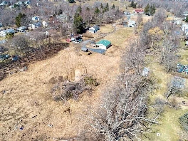Aerial view of a rural property with leafless trees, brown fields, and scattered houses.