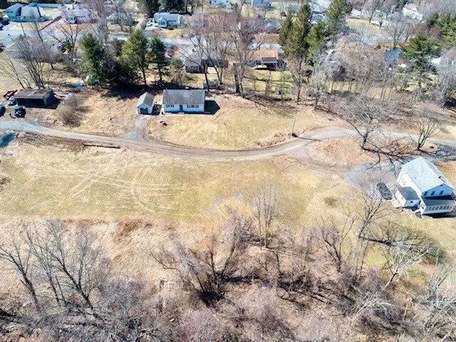 Aerial view of a rural property with two houses, a winding dirt road, and leafless trees.