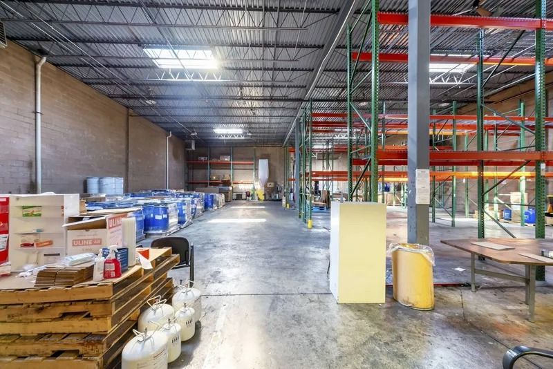 Empty warehouse interior with shelves, pallets, and stacked boxes under bright industrial lighting