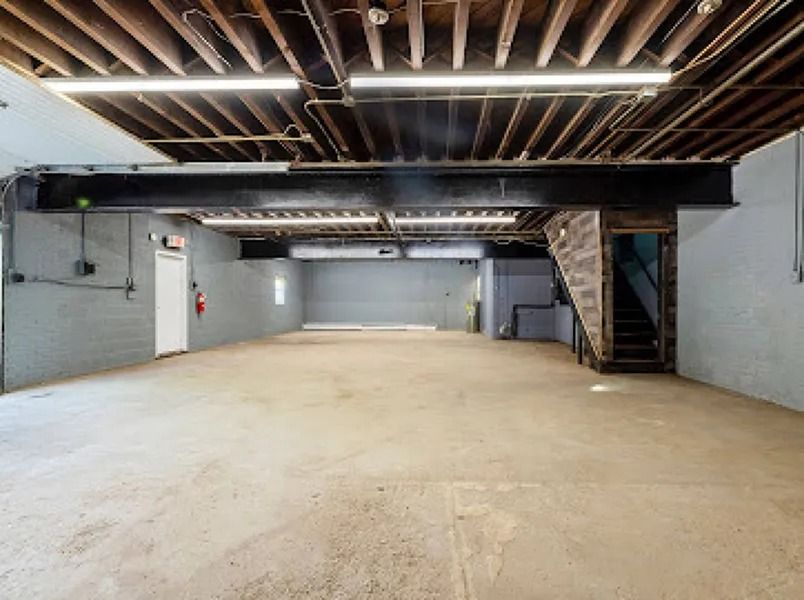 Empty unfinished basement with exposed ceiling beams and concrete floor