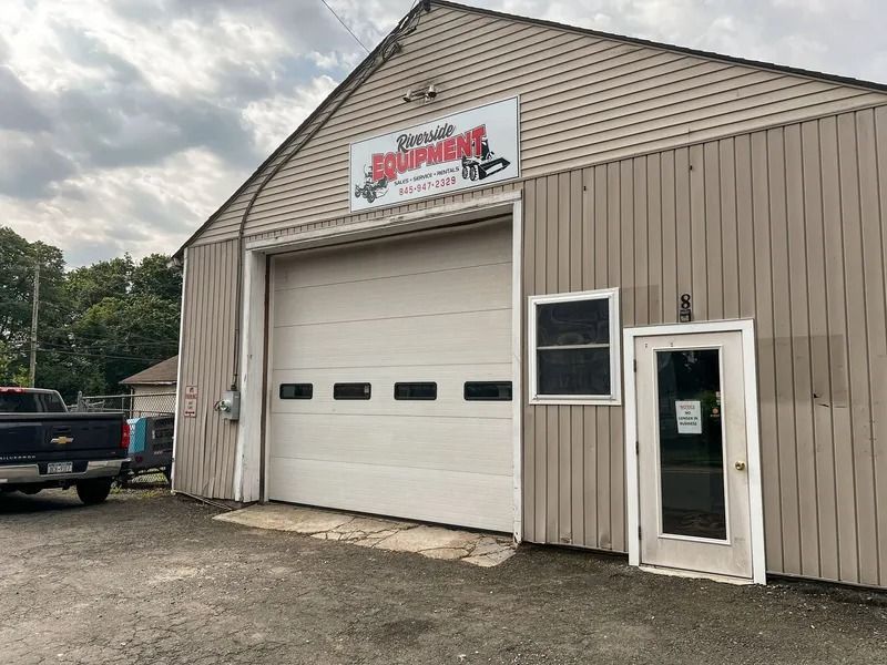Auto repair shop exterior with large garage door and a side entrance door