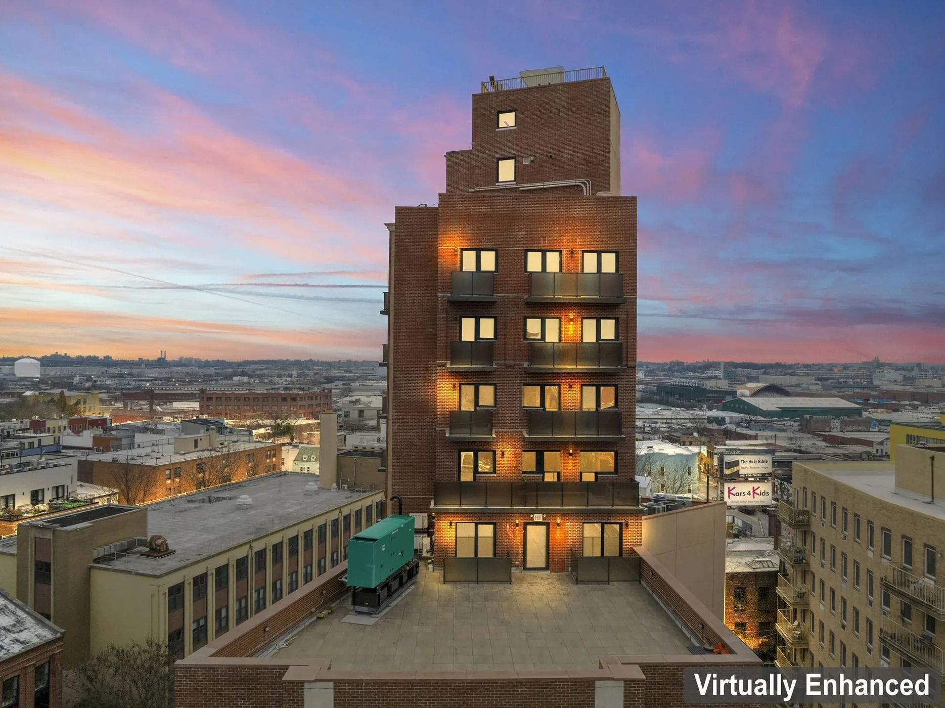 Tall brick building at sunset with glowing windows above a city skyline
