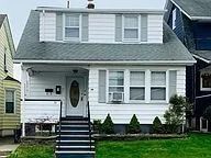 Small gray house with white trim, front steps, and a grassy yard