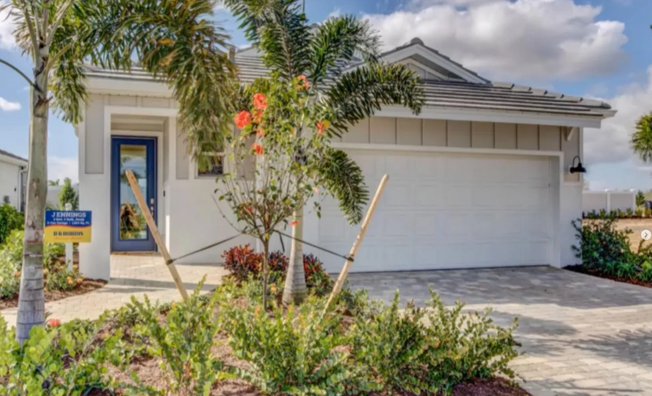 Modern single-story house with white garage door, palm trees, and landscaped front yard