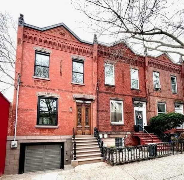 Red brick row houses with stoops and bare tree branches on a city street