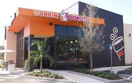Dunkin’ Donuts storefront with orange signage and a modern black exterior at a sunny street corner