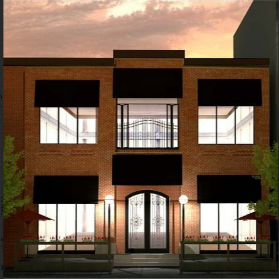 Brick townhouse facade at sunset with large windows, black awnings, and a central arched door