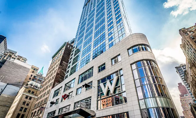 Tall modern glass office tower with a curved white facade in a city street view