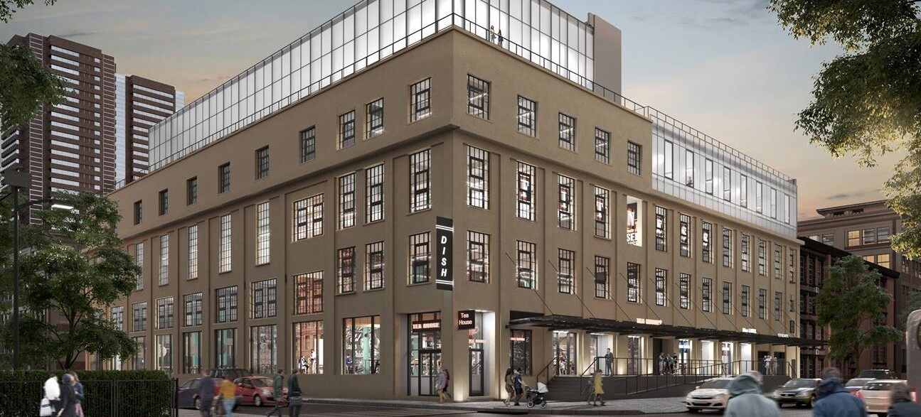 Modern brick office building at dusk with large windows and cars on the street