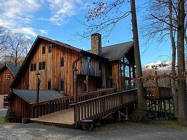 Wooden house with ramp and chimney in a wooded yard under a blue sky