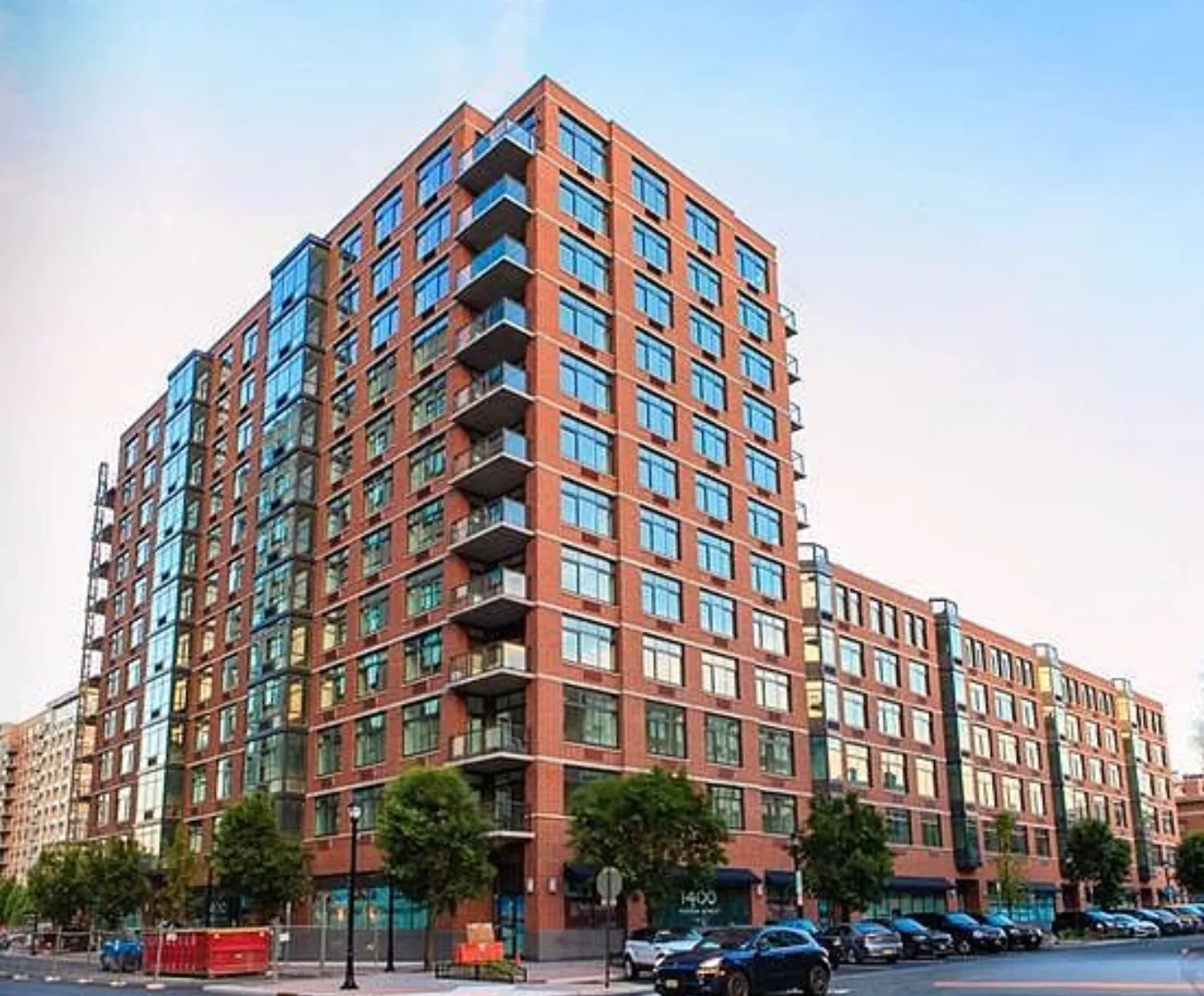 Modern red-brick apartment buildings on a city street under a pale sky