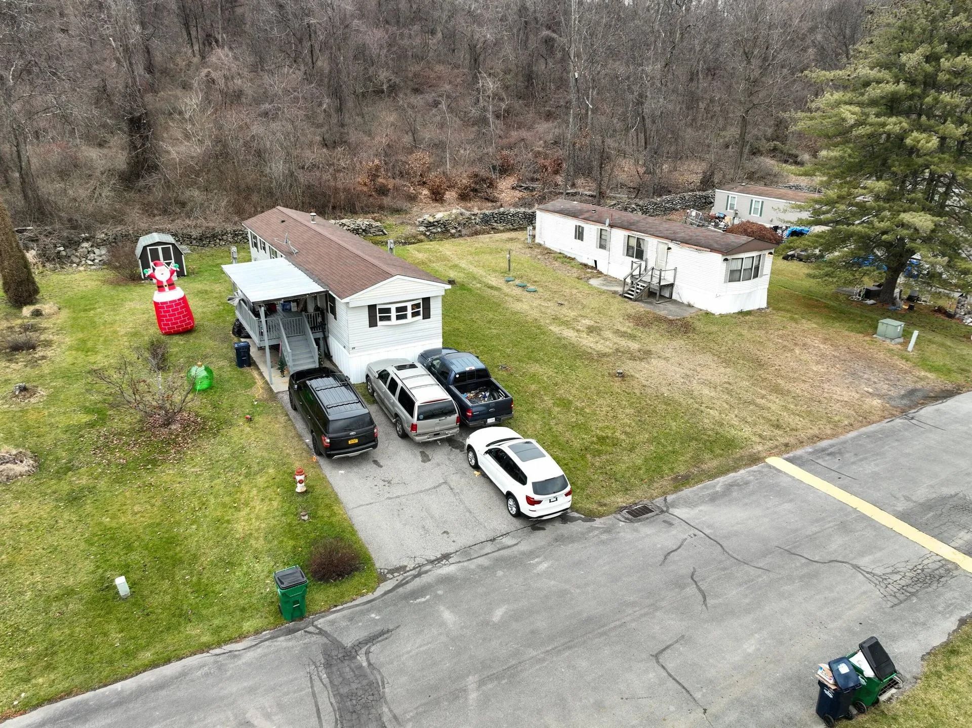 Rural yard with two mobile homes, several parked vehicles, and a person in red near the left house.
