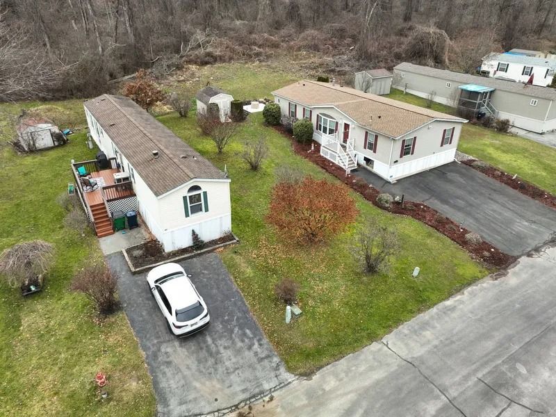 Aerial view of two mobile homes with cars parked on driveways in a grassy residential area