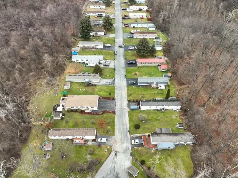 Aerial view of a small residential street with trailers and houses surrounded by woods.